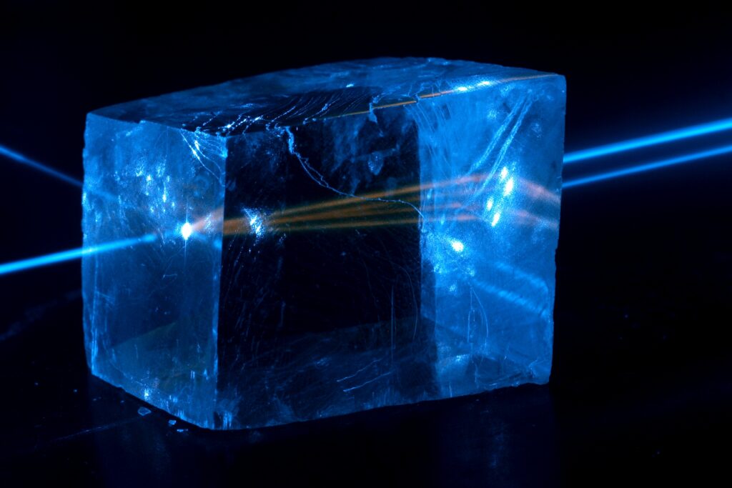 Фотоны испускаются голубым лазерным лучом снаружи, оранжевым лазерным лучом внутри кальцита и его флуоресценцией